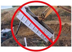 Dump truck being cleaned out with a back hoe